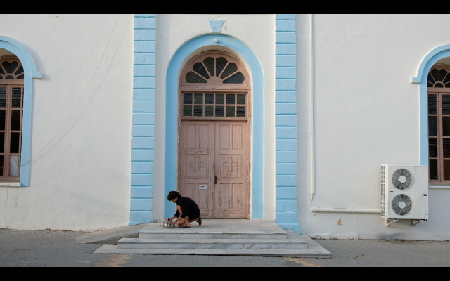 Paula in front of the church at Pitsidia, film still 'The Logistics of Paradise', (c) Paula Hildebrandt